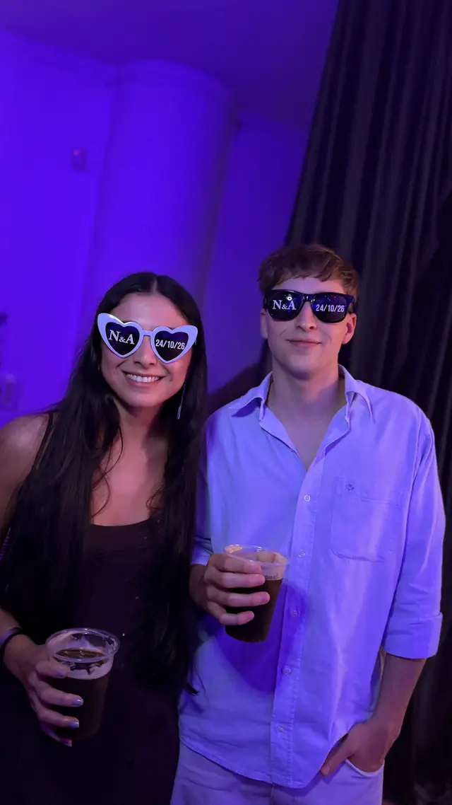 Pareja de invitados con anteojos de la boda, bajo luces violetas